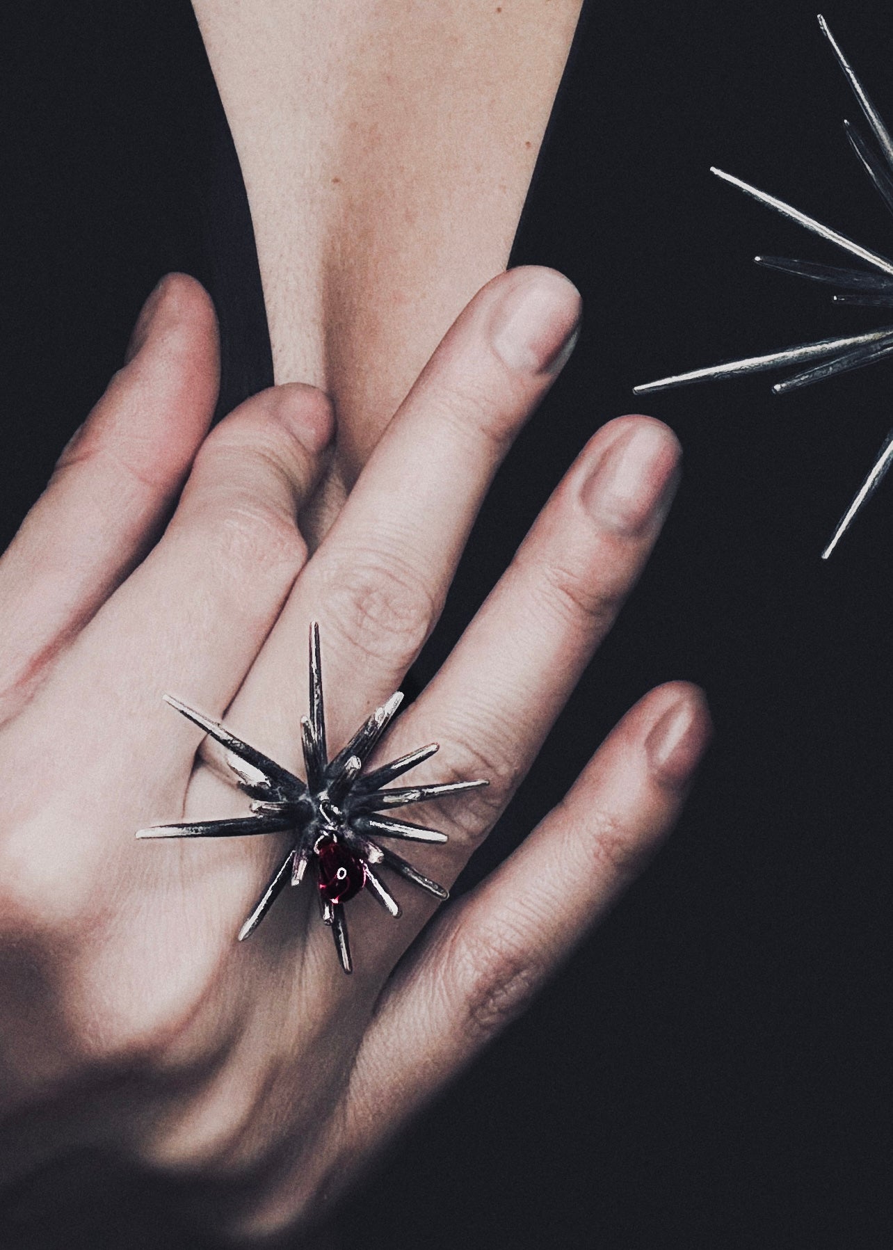 Sterling silver statement ring with dark patina spike form and movable red crystal accent, contemporary sculptural jewelry