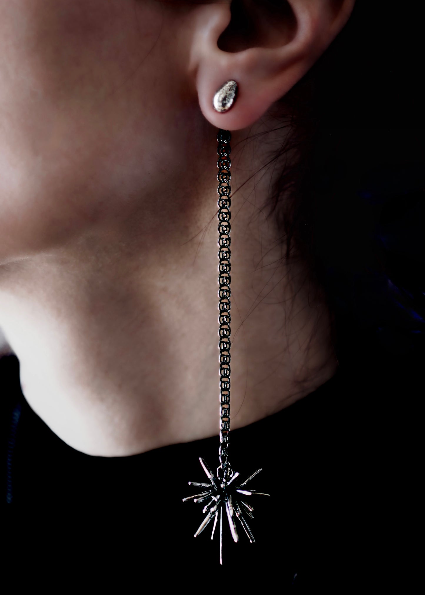 Sterling silver asymmetrical earring set with spike drop chain and beam stud worn on ear