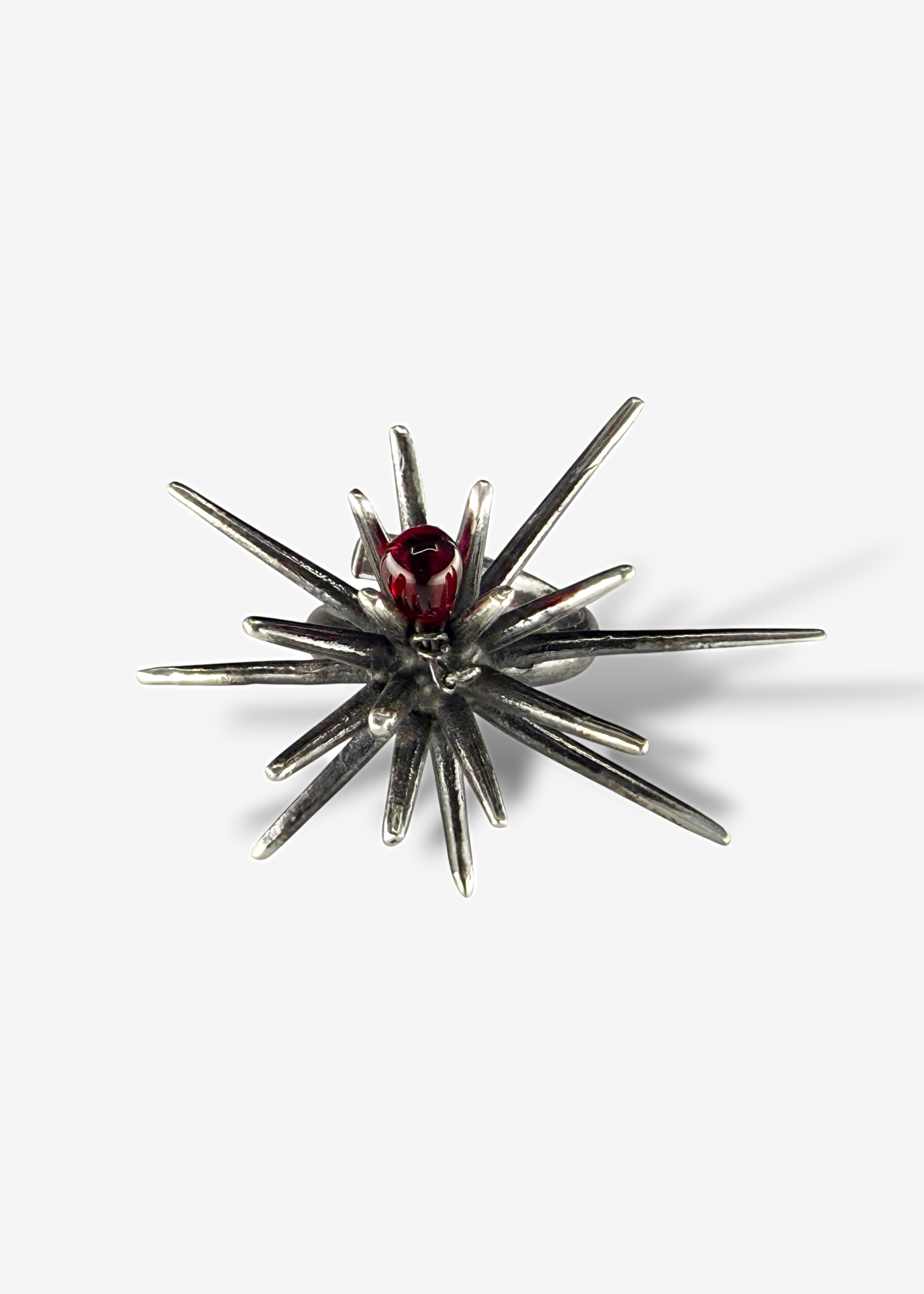 Top view of sterling silver Beam Afterlight ring with radial spike design and central red Czech crystal, dark oxidized finish