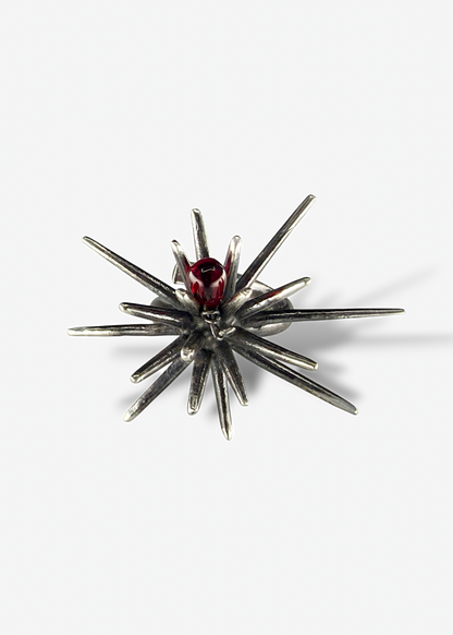 Top view of sterling silver Beam Afterlight ring with radial spike design and central red Czech crystal, dark oxidized finish