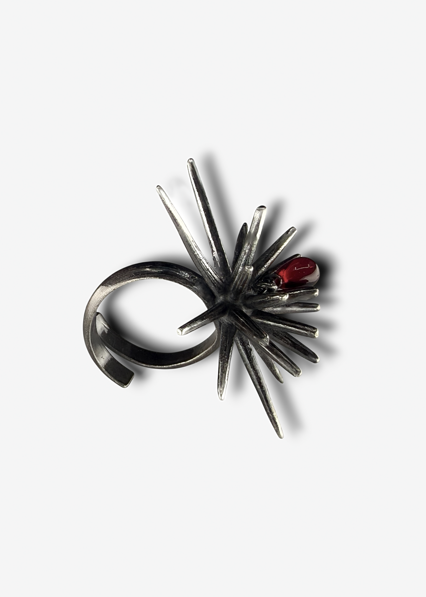 Large sculptural sterling silver ring with spike structure and red crystal detail worn on finger, bold adjustable statement ring