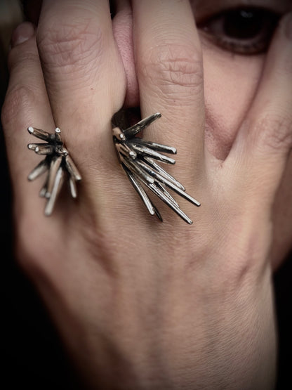 close up of hand near face wearing sterling silver spike ring with clustered sharp elements