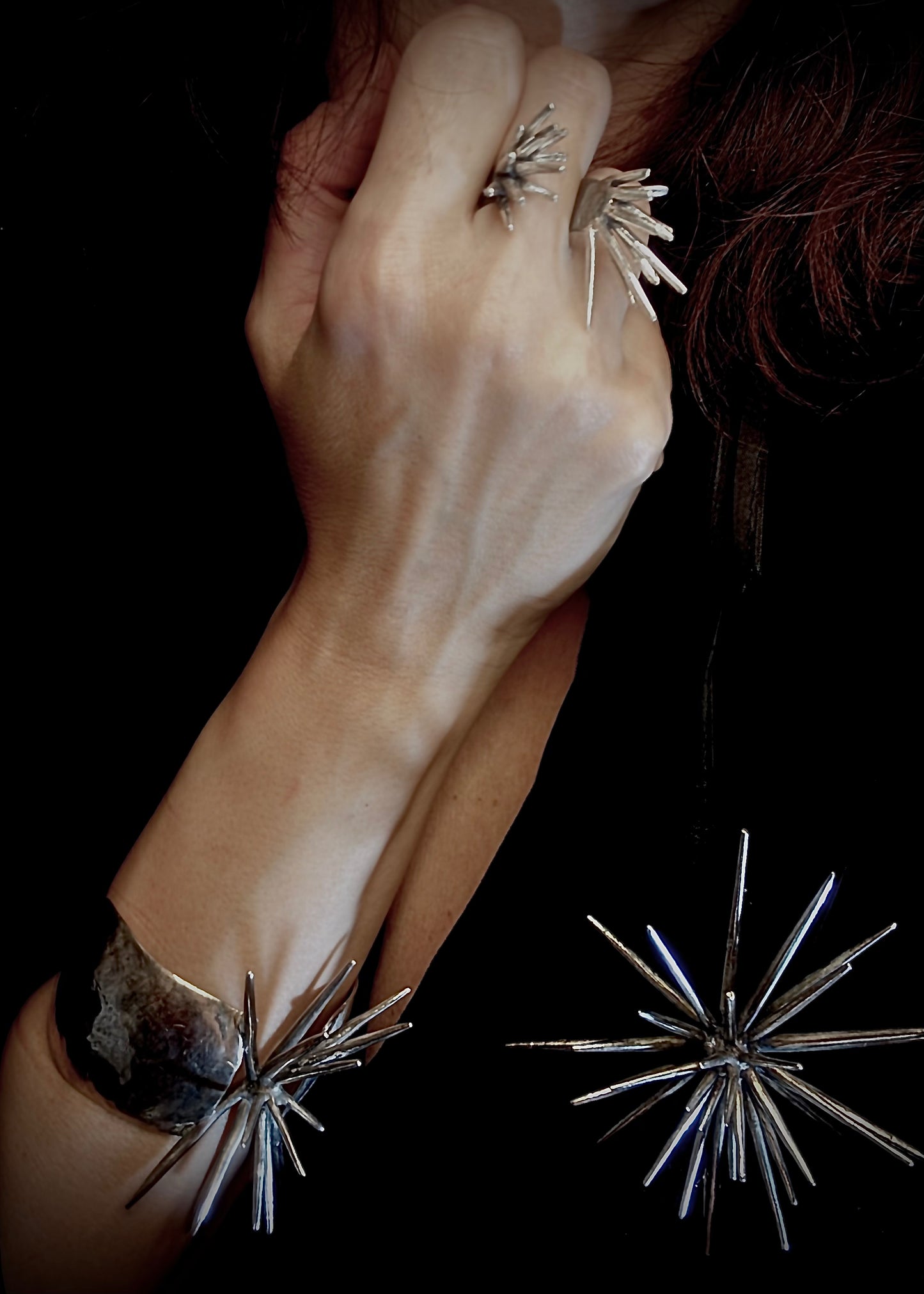 model wearing sterling silver spike ring with opposing forms paired with sculptural  brooch and bracelet on wrist