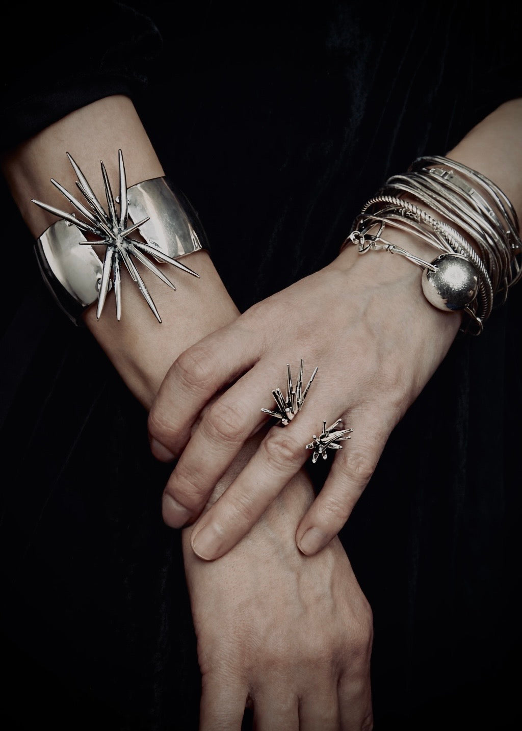 Sterling silver spike cuff bracelet worn on wrist with sculptural rings and bangles Beam Collection statement jewelry styling