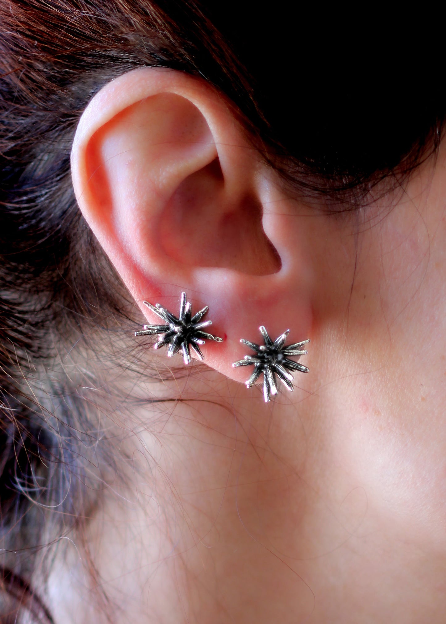 Handmade sterling silver Beam stud earrings by Ninimosi worn on ear, sculptural spike design showing pair and scale