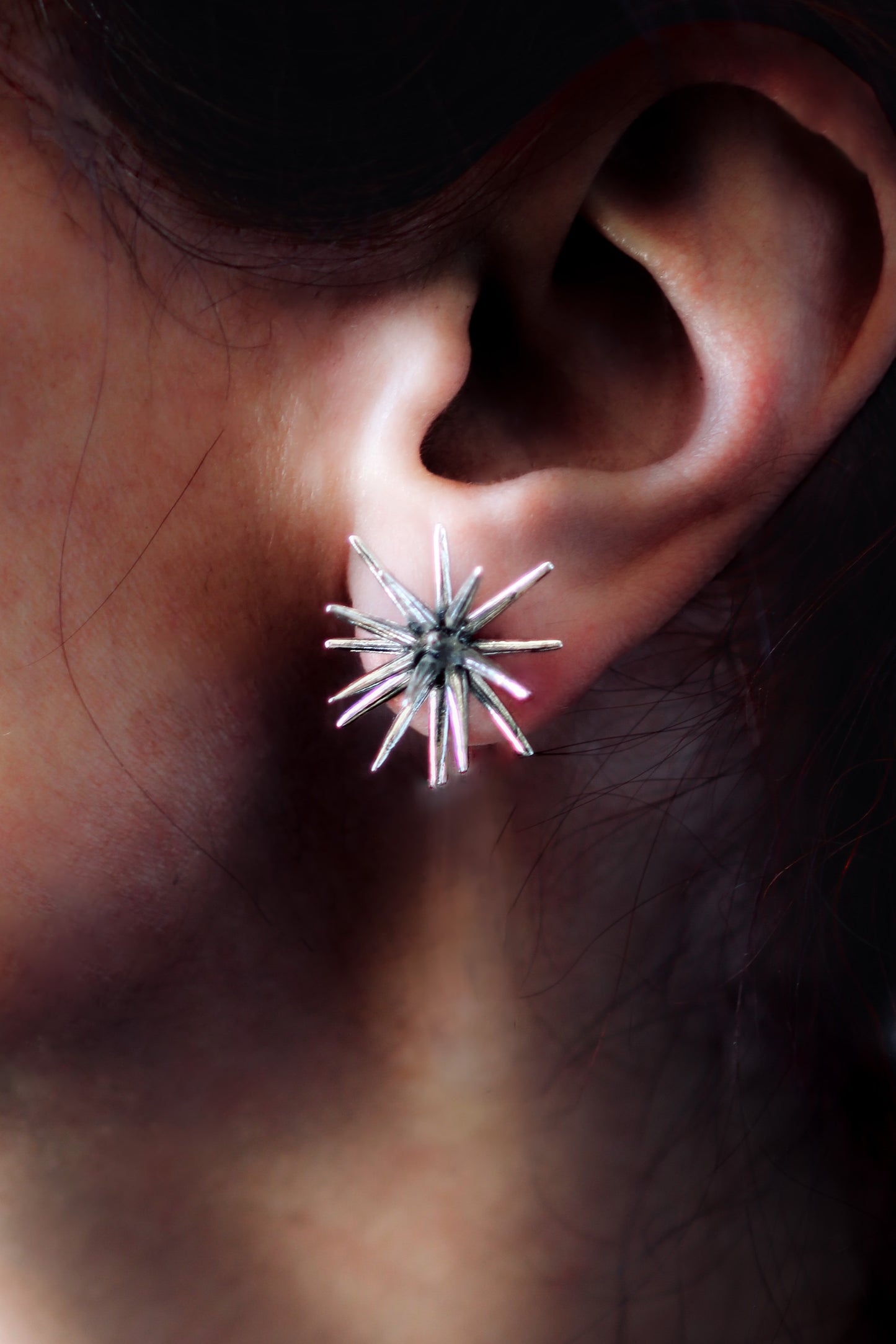 Handmade sterling silver Beam stud earring by Ninimosi worn on ear, sculptural spike design catching light