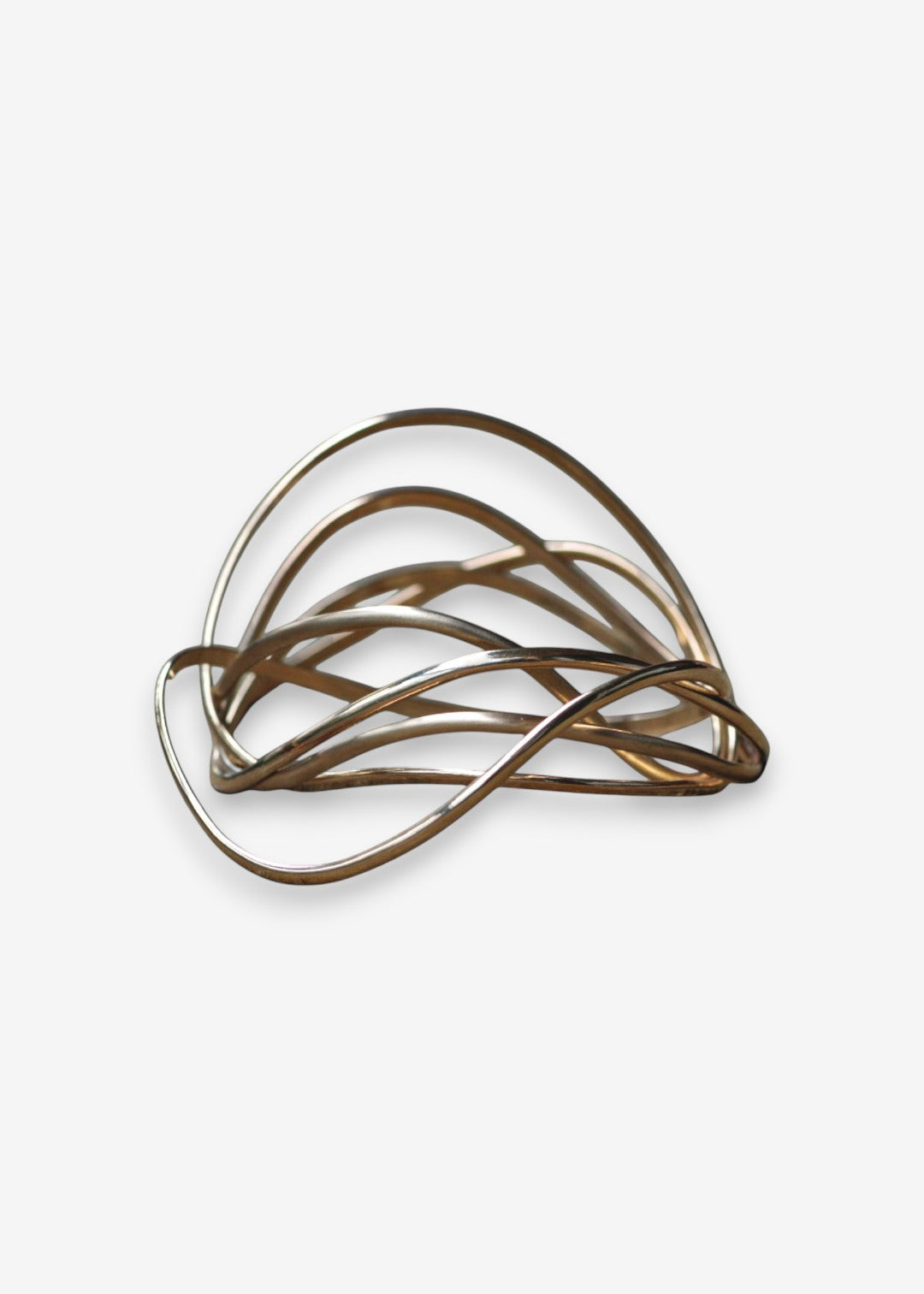 Sculptural wave bangle stack in gold tones on a clean background