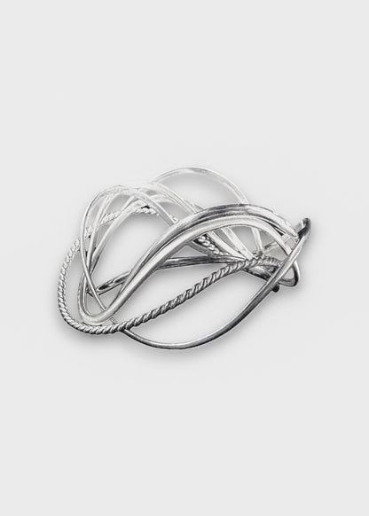 handcrafted silver wave bangle stack on neutral background, sculptural stackable jewelry